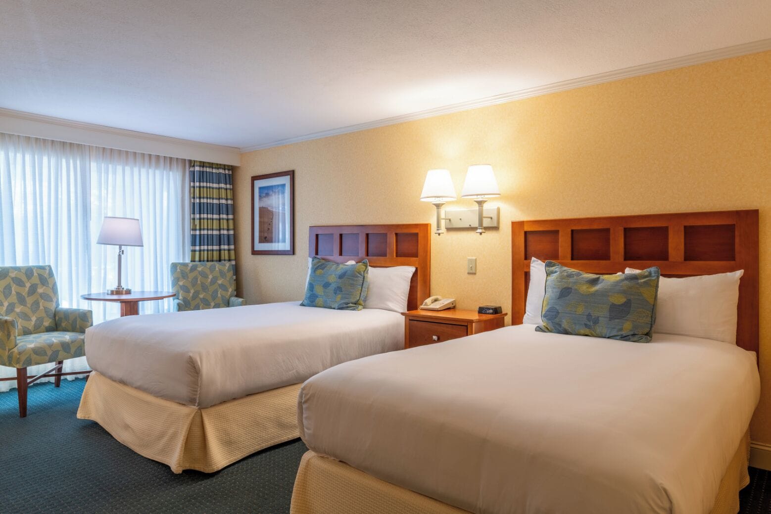 Une chambre d’hôtel avec deux lits, une chaise, une table et une lampe.
