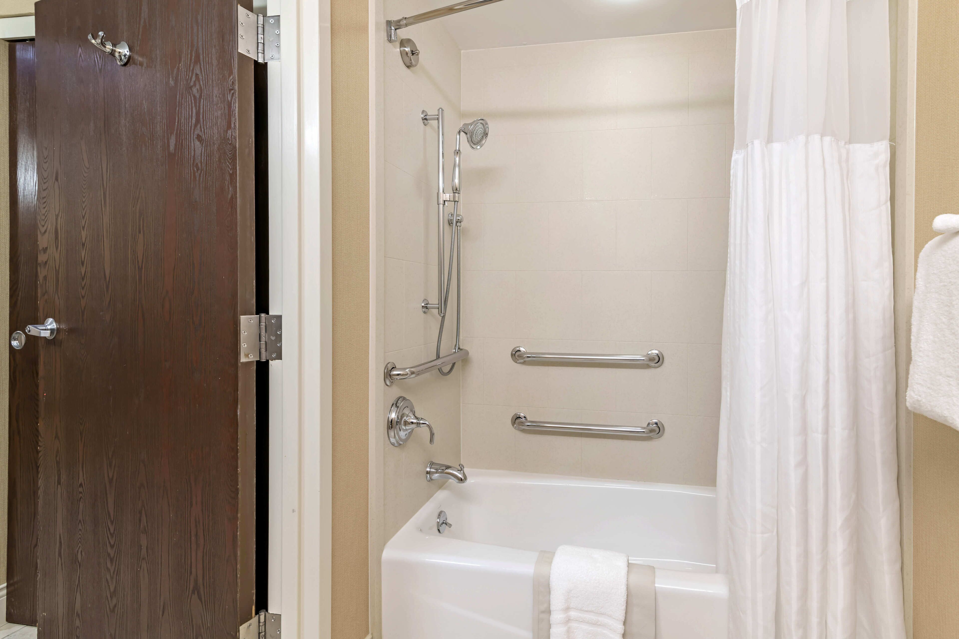 Un baño con bañera, ducha y puerta de madera.