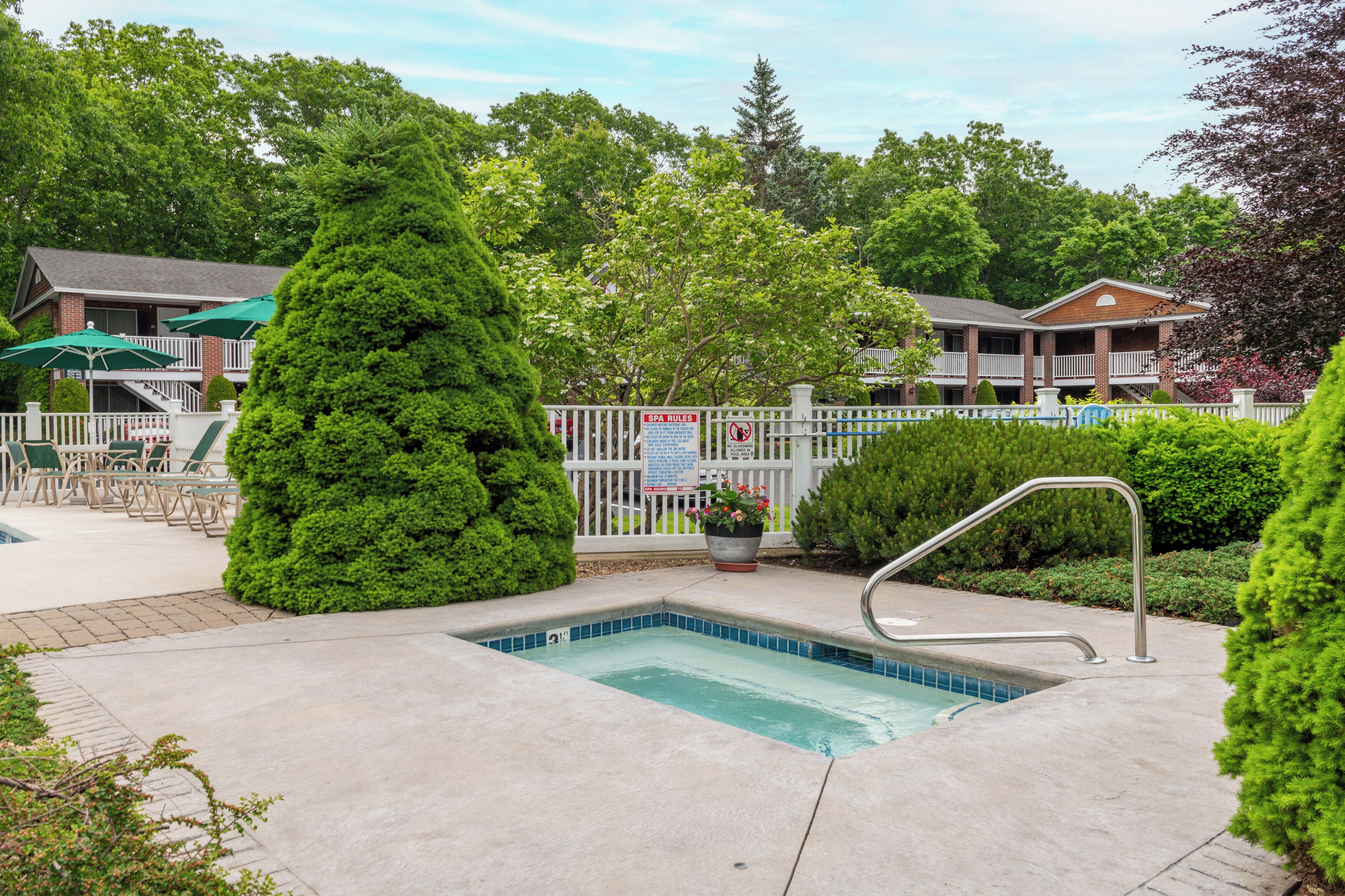 A swimming pool with a metal ladder, surrounded by a white fence, and a sign indicating no swimming.