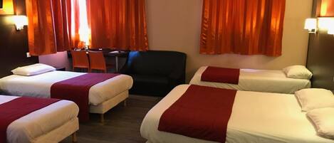Habitación de hotel con cuatro camas, un escritorio y dos sillas.