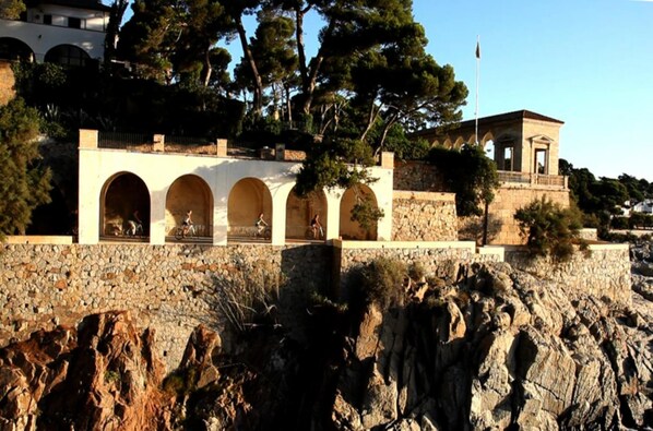 A stone building with arched windows and a flagpole.
