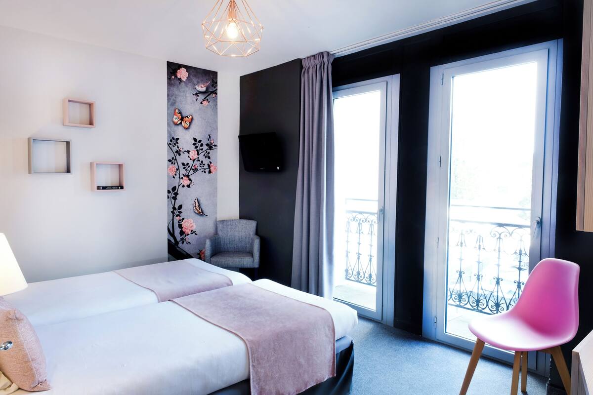 A hotel room with a bed, a chair, a TV, and a balcony with a view.