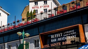 A hotel named 'Hotel Sainte Rose' with a balcony adorned with red flowers and a sign for 'Buffet Bar-Restaurant' below it. - Hotel Sainte Rose (Lourdes)