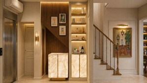 A modern interior with a marble floor, a wooden panel wall, a staircase with a railing, and a shelf with decorative items. - Hôtel Beauvoisin (Paris)