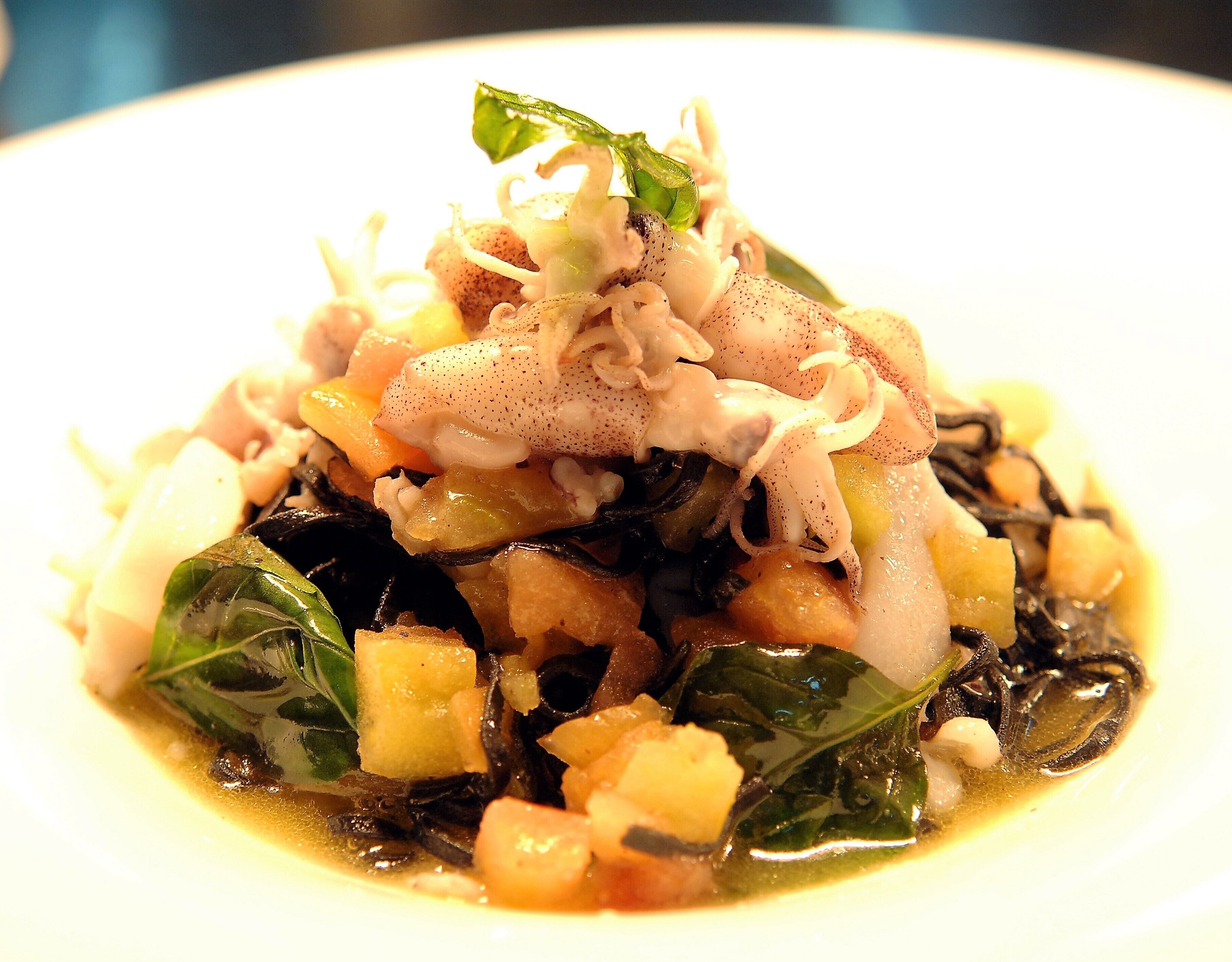 A dish with various ingredients, including greens, potatoes, and possibly seafood, served on a white plate.