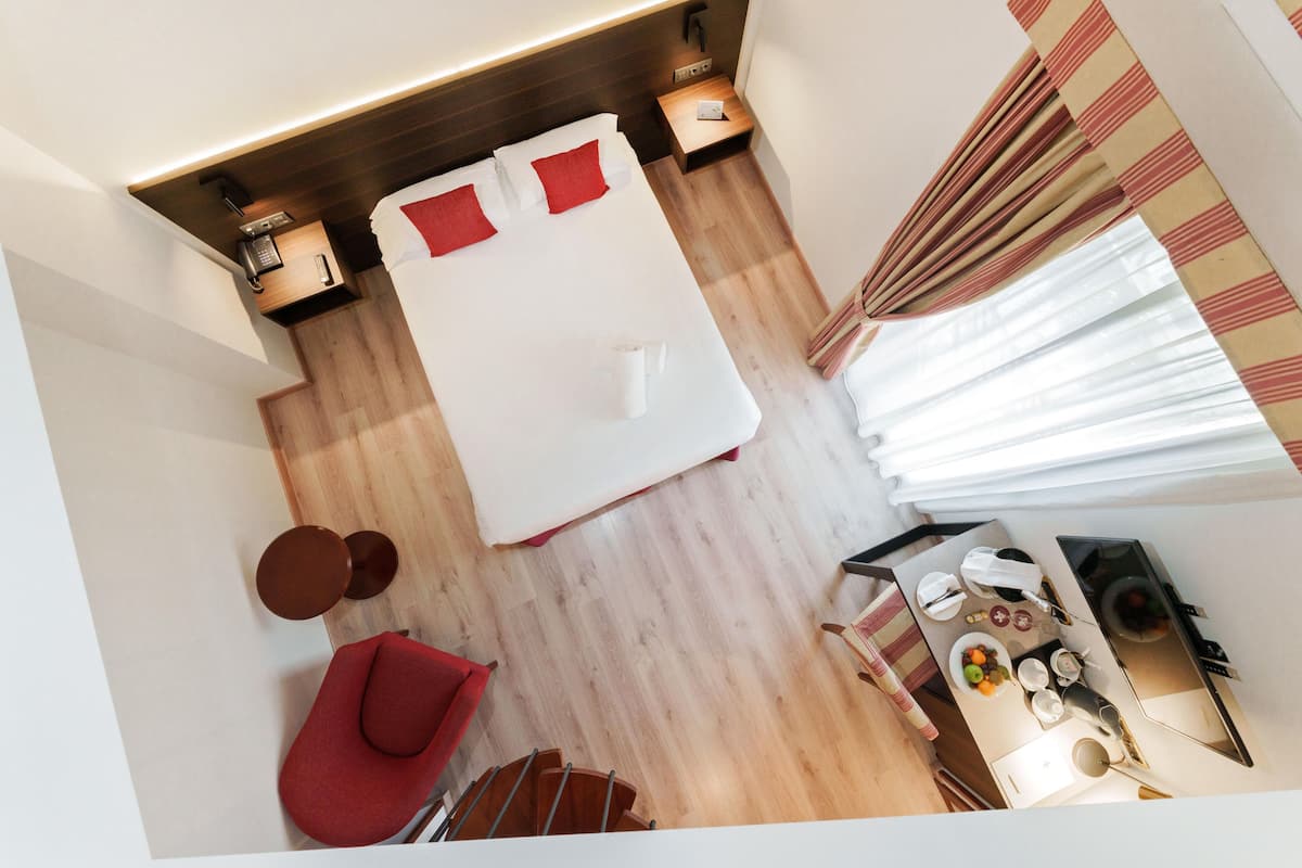 Una habitación de hotel con una cama, una mesita pequeña con un hervidor, una silla y un área de comedor con una mesa y sillas.