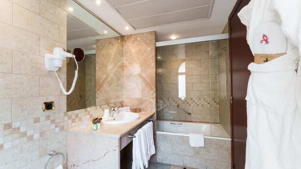 Een moderne badkamer met een grote spiegel, een haardroger, een wastafel en een bad.
