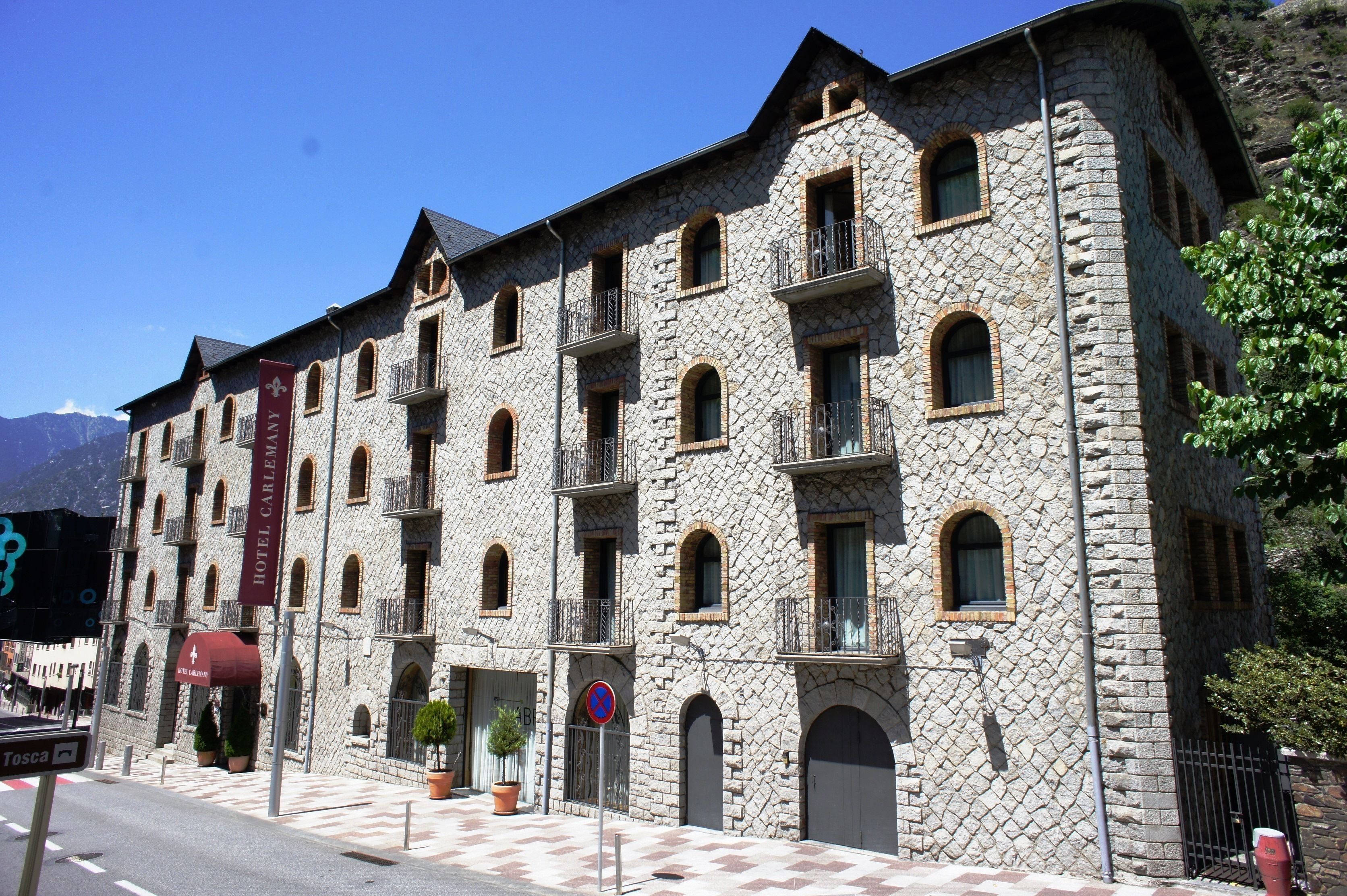 Un edificio de piedra con varios balcones y ventanas arqueadas, presumiblemente un hotel.