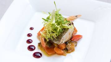 Un plato blanco con un guiso de pescado, verduras y una guarnición.
