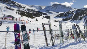 Een besneeuwde piste met snowboarden en ski's die tegen een hek leunen.