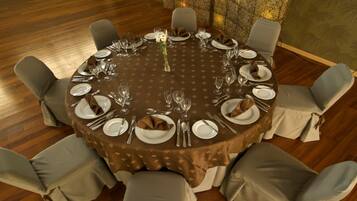 A round dining table with a brown tablecloth, surrounded by grey upholstered chairs.