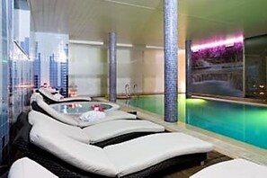 A modern spa area with a pool, lounge chairs, and a glass-enclosed space.