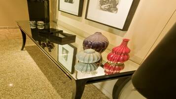 Una mesa con cubierta de vidrio, jarrones decorativos y cuadros en una pared.