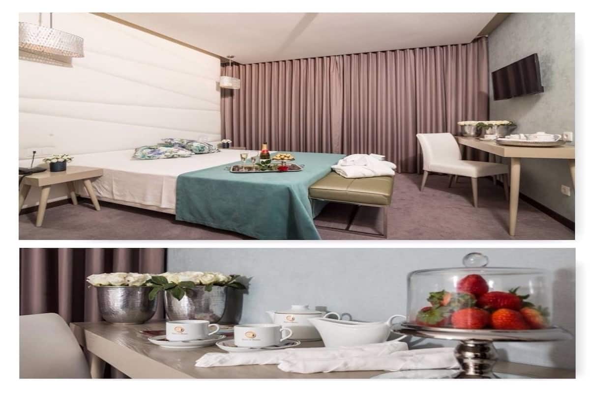 Hotelkamer met een bed, een bureau, een stoel, een televisie en een zithoek met een gedekte tafel voor thee.