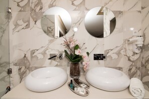 A bathroom with two sinks, a mirror, a plant, and a towel rack.