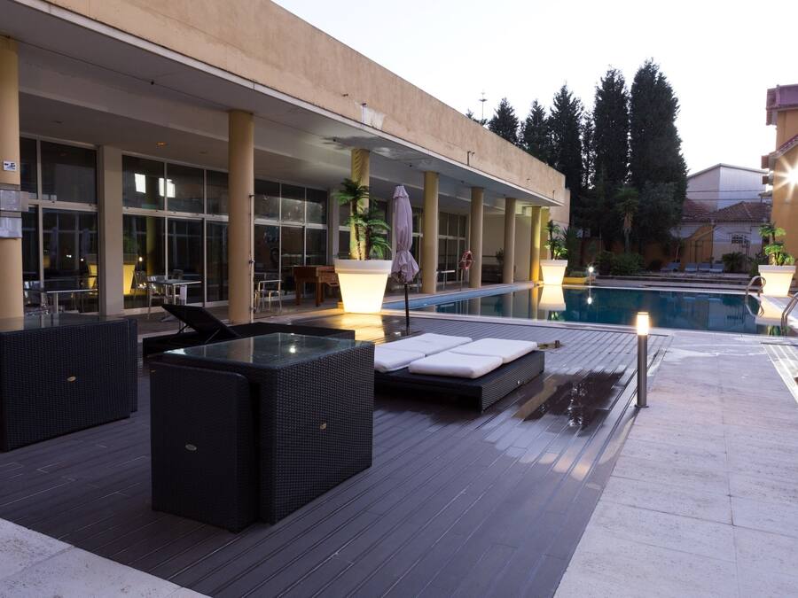 Zona de piscina con asientos al aire libre, una piscina y un paseo cubierto.