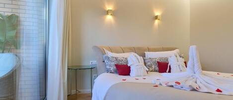 A hotel room with a bed, two wall-mounted lights, a glass partition, and a small table.