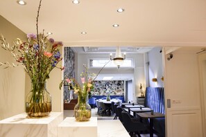 A modern dining area with marble countertops, two vases with flowers, and a chandelier. - Boutique Hotel Asterisk, a family run hotel (Amsterdam)