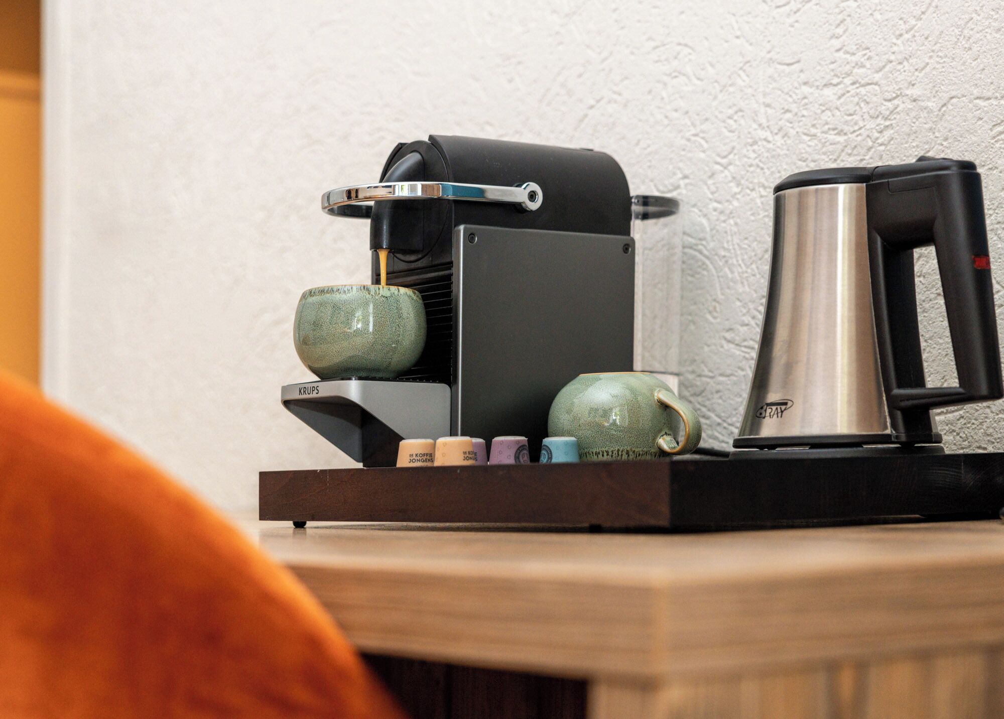 Una cafetera con una tetera y una taza sobre una bandeja de madera.