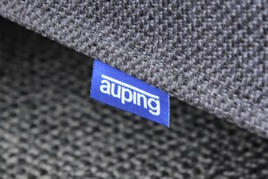 Gros plan sur la texture d’un tissu, avec une étiquette bleue portant l’inscription « auping ».