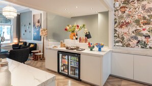 A modern kitchen with a marble countertop, a built-in mini-fridge, and a decorative wall with a tropical print. - Boutique Hotel Asterisk, a family run hotel (Amsterdam)