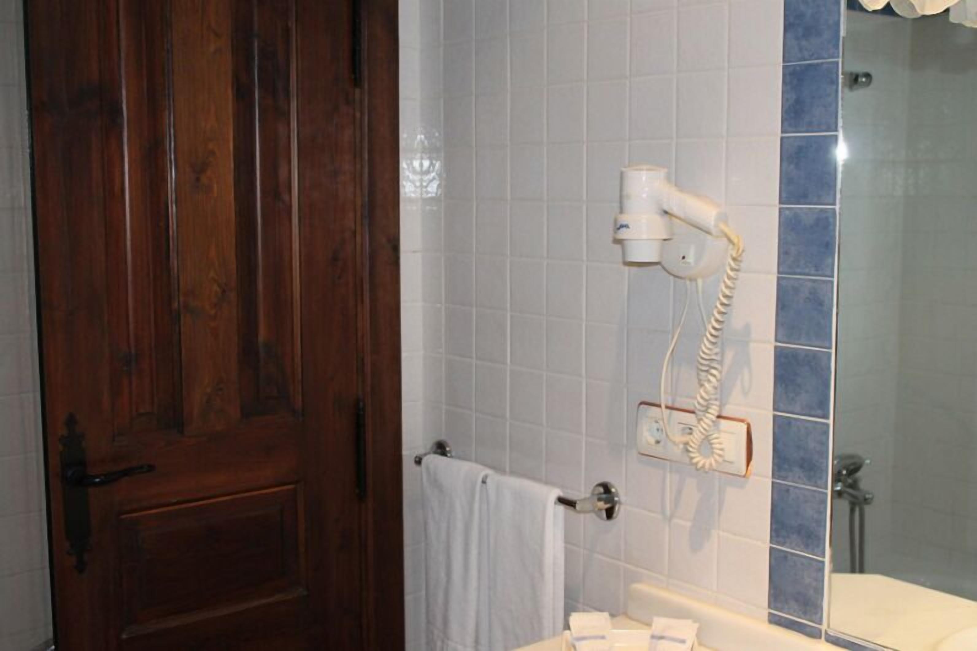 A bathroom with a wooden door, a towel rack, a hairdryer, and a bathtub.