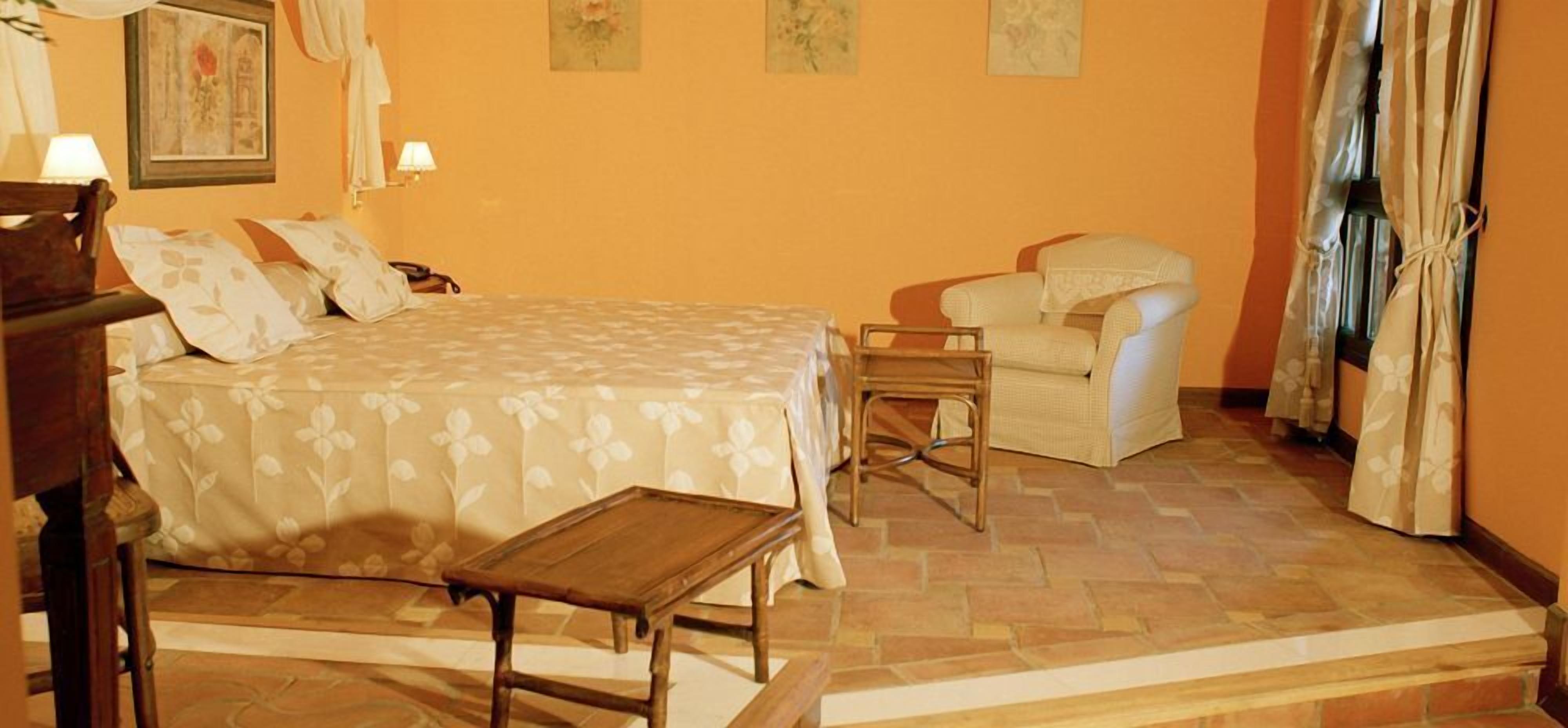 A bedroom with a bed, a wooden nightstand, a chair, and a small table.