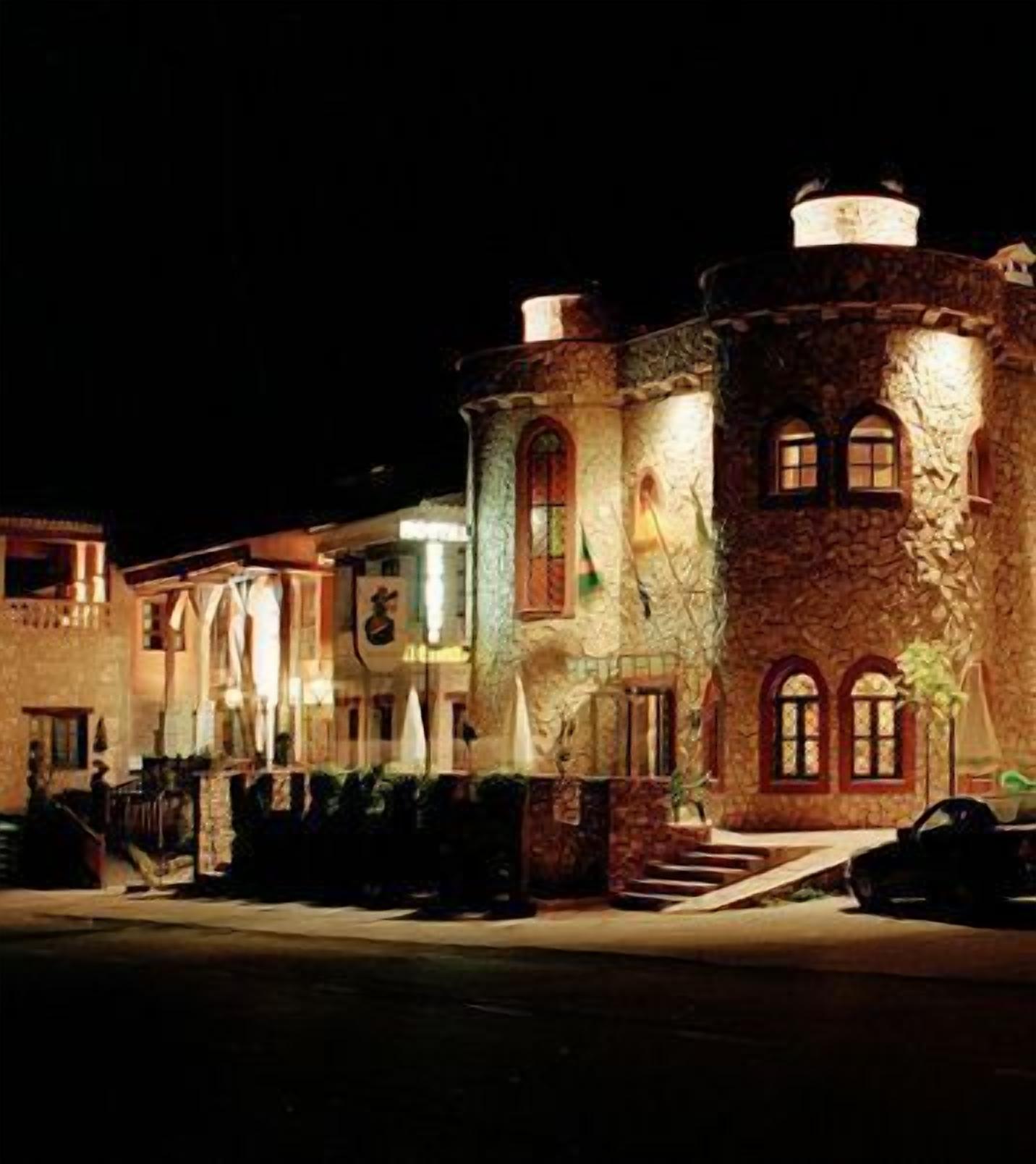 Edificio histórico con ventanas de arco y fachada de piedra, iluminado por la noche.
