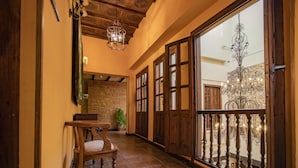 A corridor with wooden doors, a chandelier, and a view of a balcony with lights.