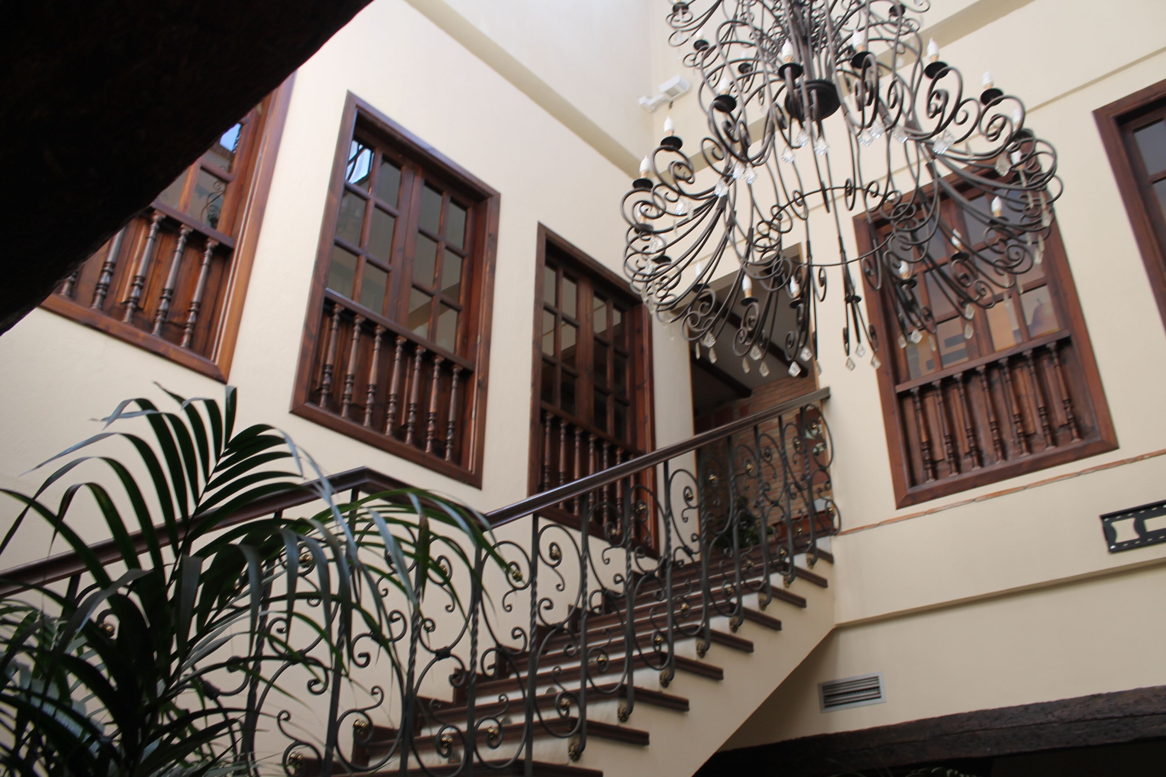 Una escalera con barandillas de hierro ornamentadas y un candelabro.