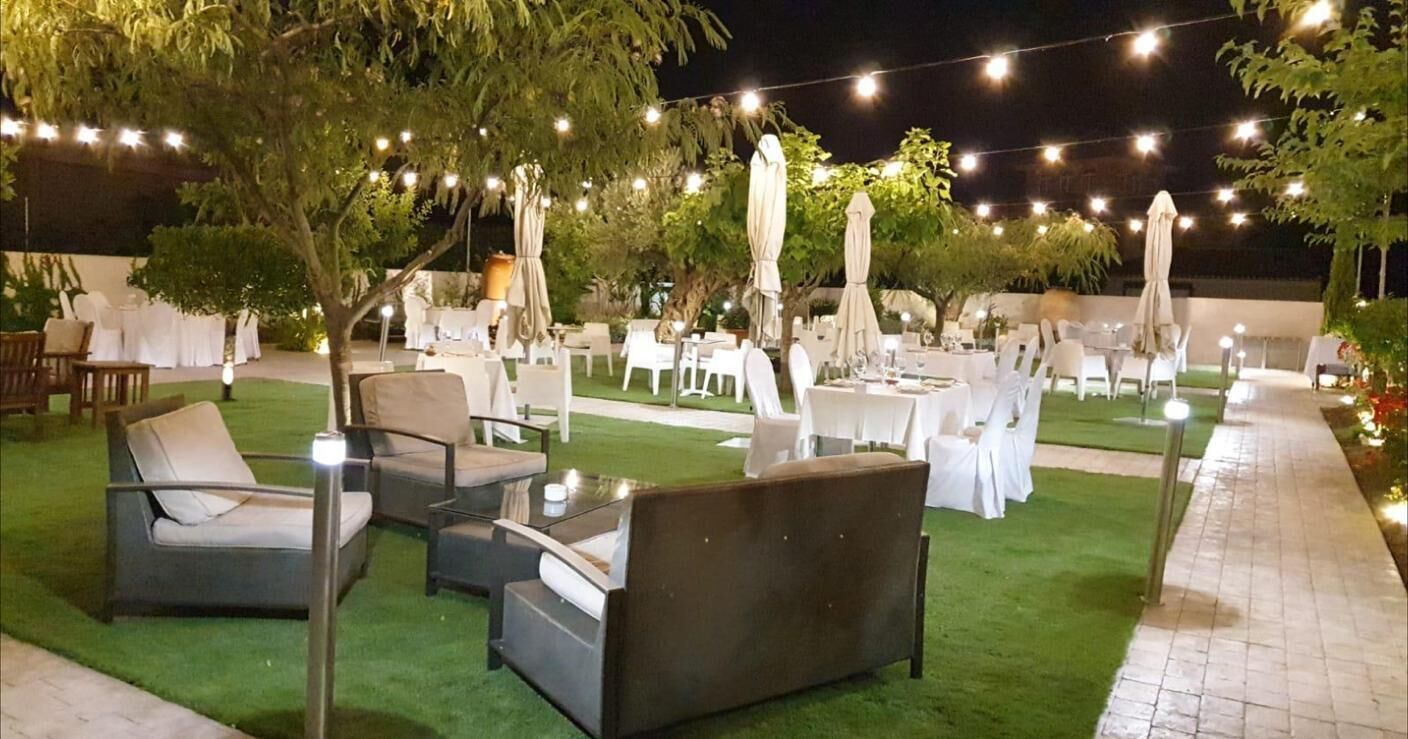 An outdoor dining area with tables and chairs, string lights, and umbrellas.
