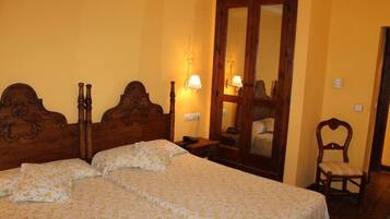 Una habitación con una cama doble, dos mesitas de noche, una silla y un espejo.