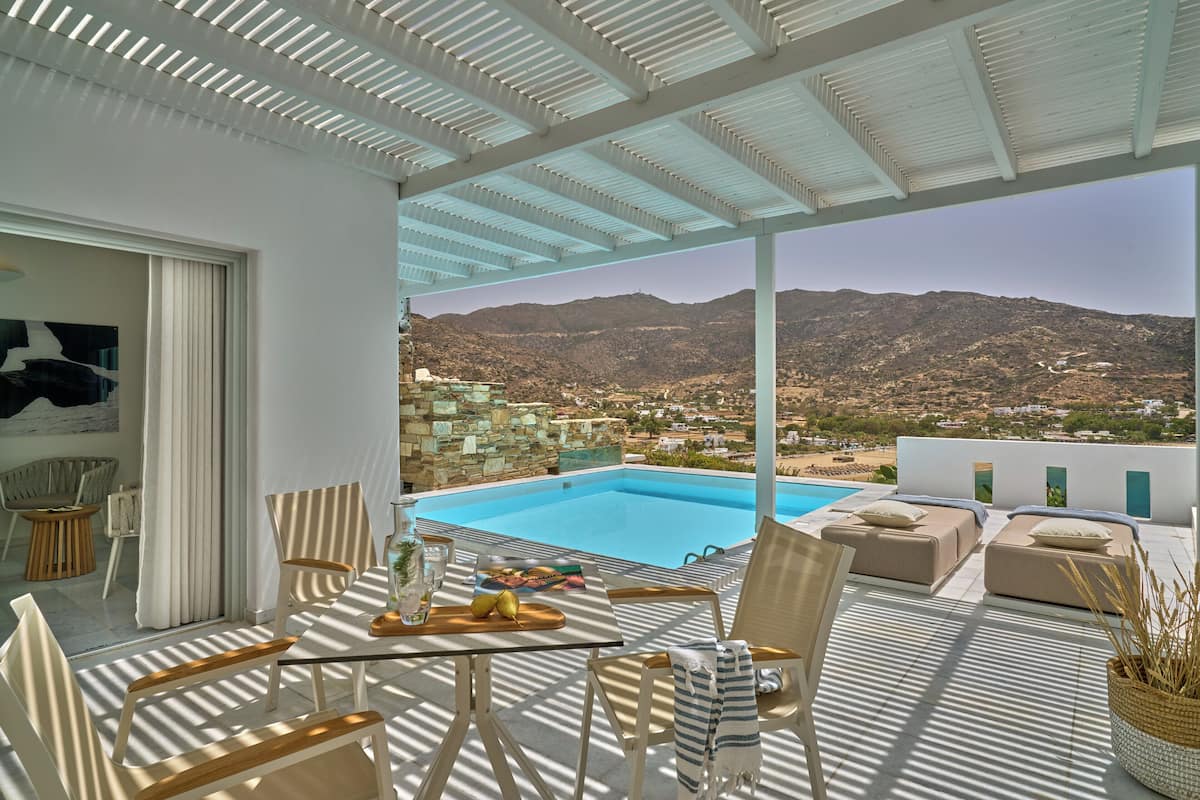 A terrace with a pool, outdoor seating, and a view of the mountains.