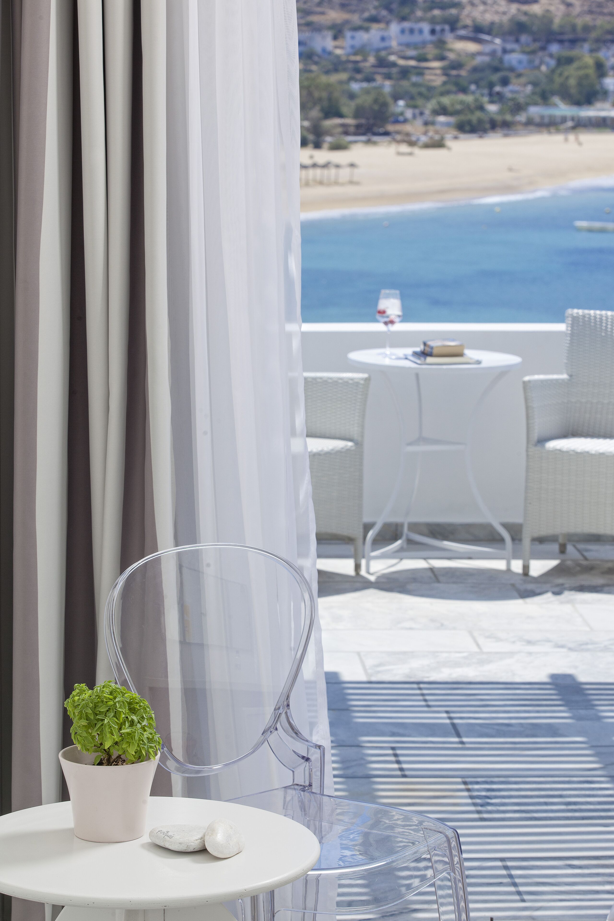 A clear view of a balcony with a white table, a potted plant, and a clear chair.
