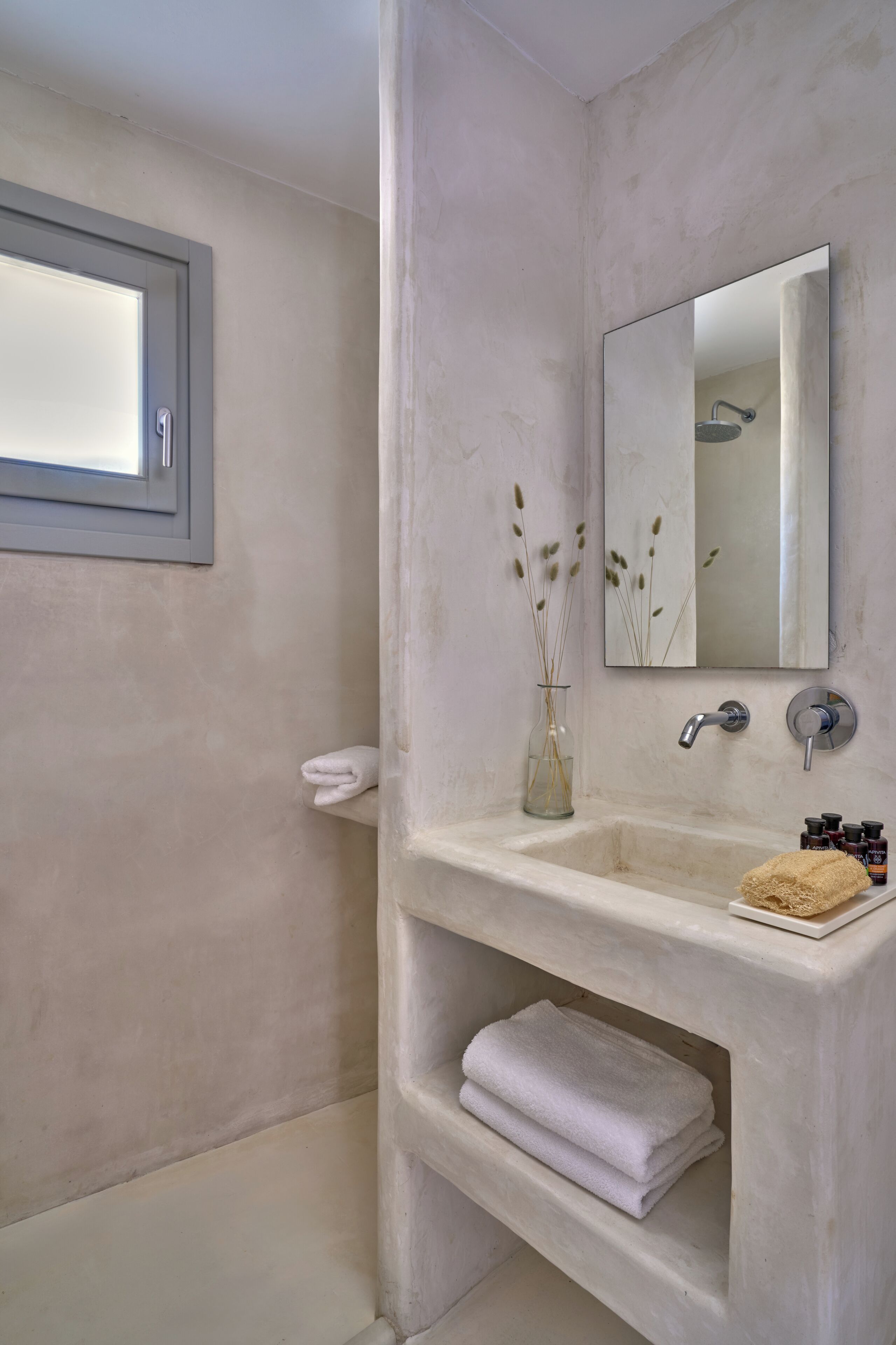 A bathroom with a large mirror, a sink with a towel rack, and a glass vase with reeds.