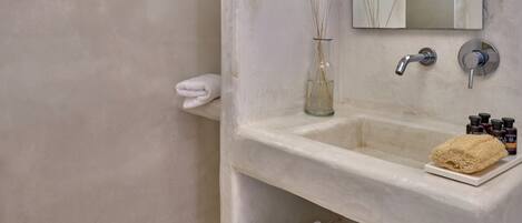 A bathroom with a large mirror, a sink with a towel rack, and a glass vase with reeds.