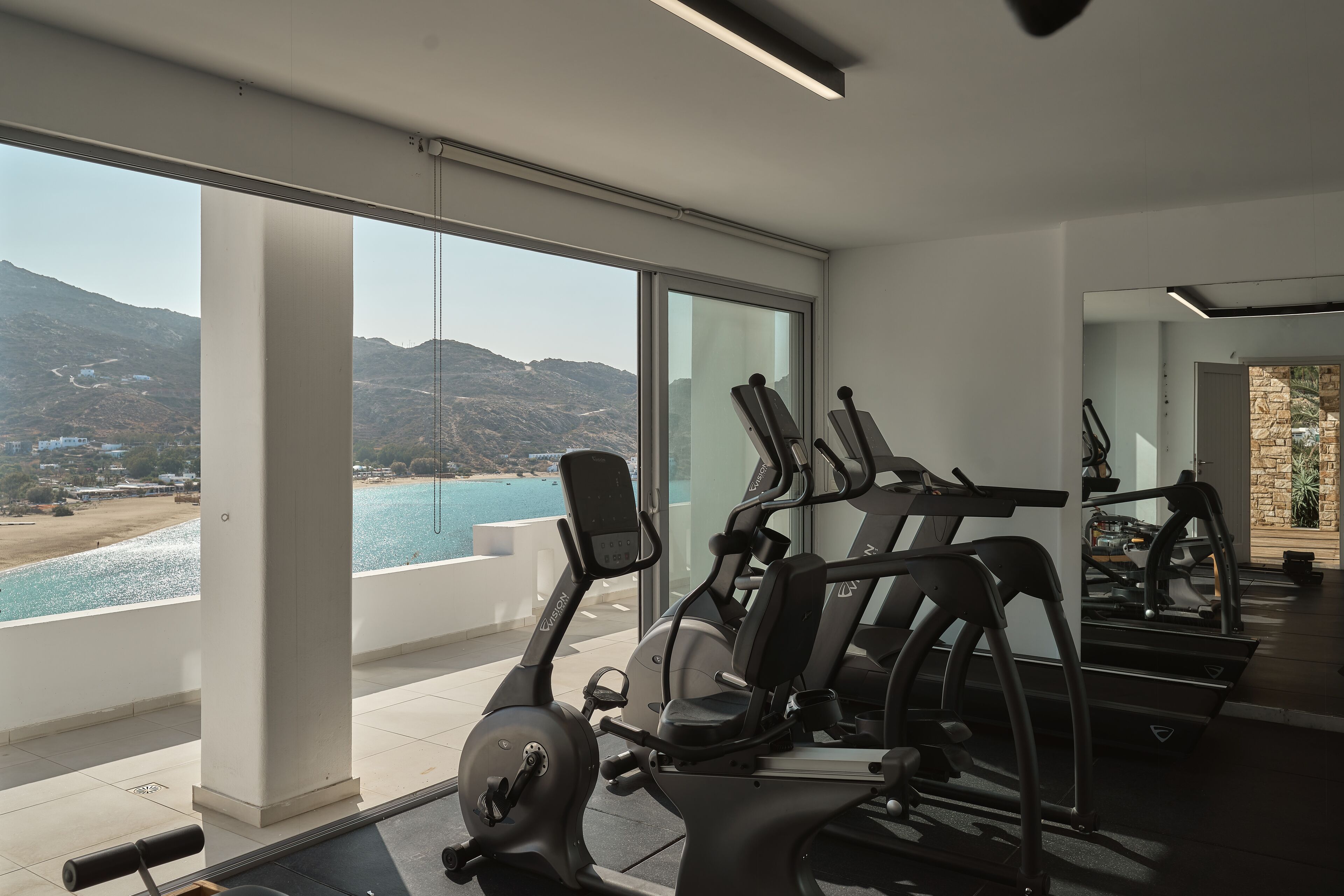 Un gimnasio con equipo de ejercicio y un amplio ventanal con vistas panorámicas.
