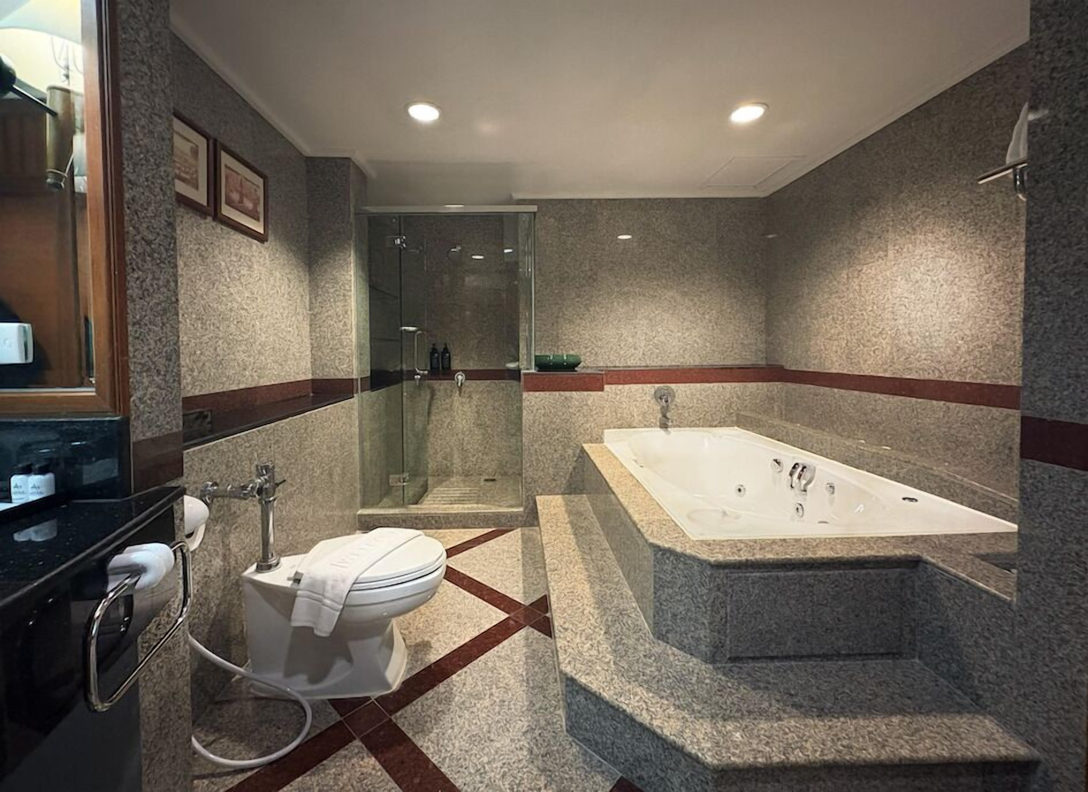 Une salle de bain moderne dotée d’une douche à parois de verre, d’une baignoire sur pieds et de toilettes avec un porte-serviettes.
