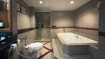 Une salle de bain moderne dotée d’une douche à parois de verre, d’une baignoire sur pieds et de toilettes avec un porte-serviettes.