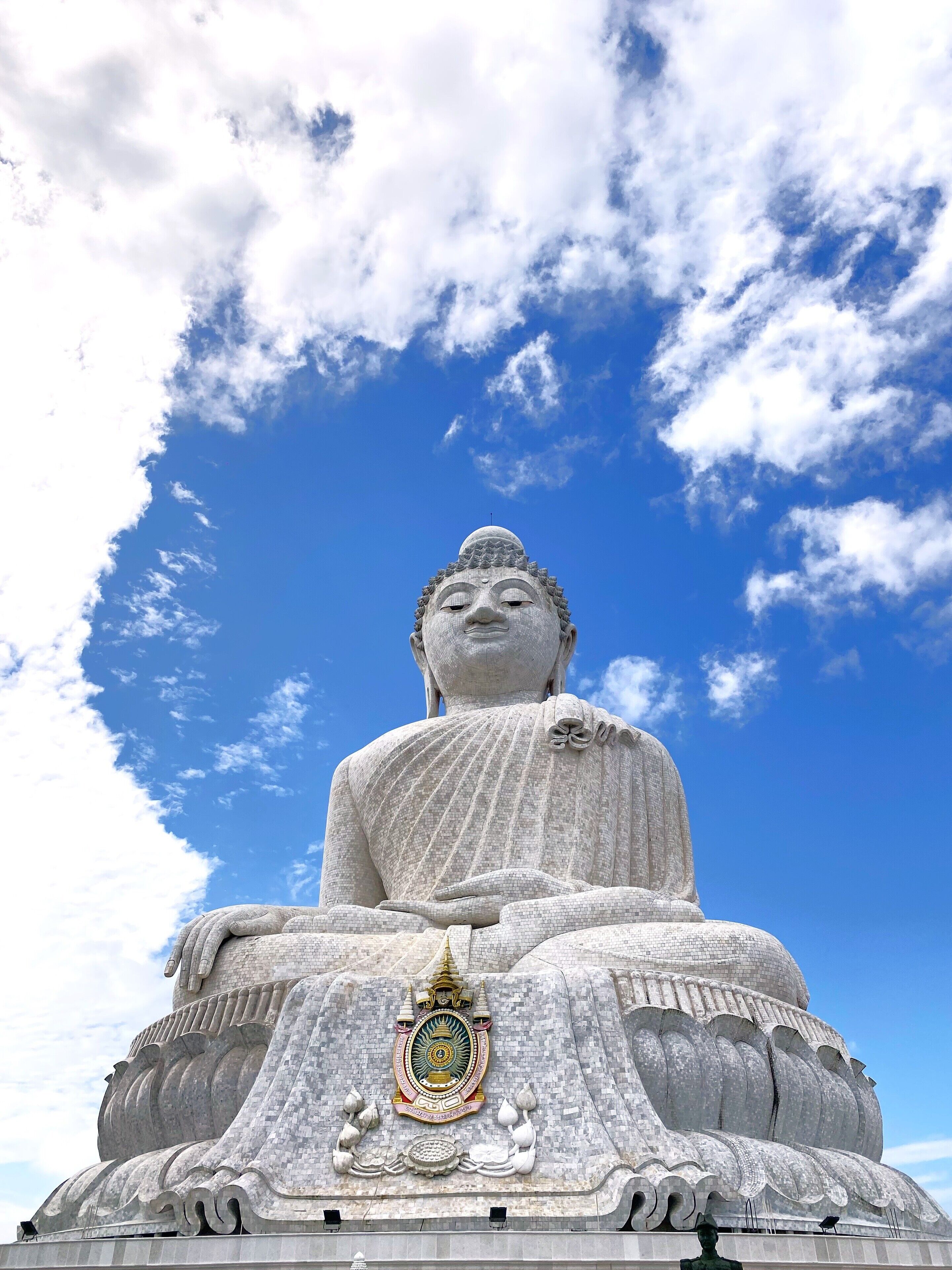 A large seated statue with intricate carvings and a detailed emblem at its base.