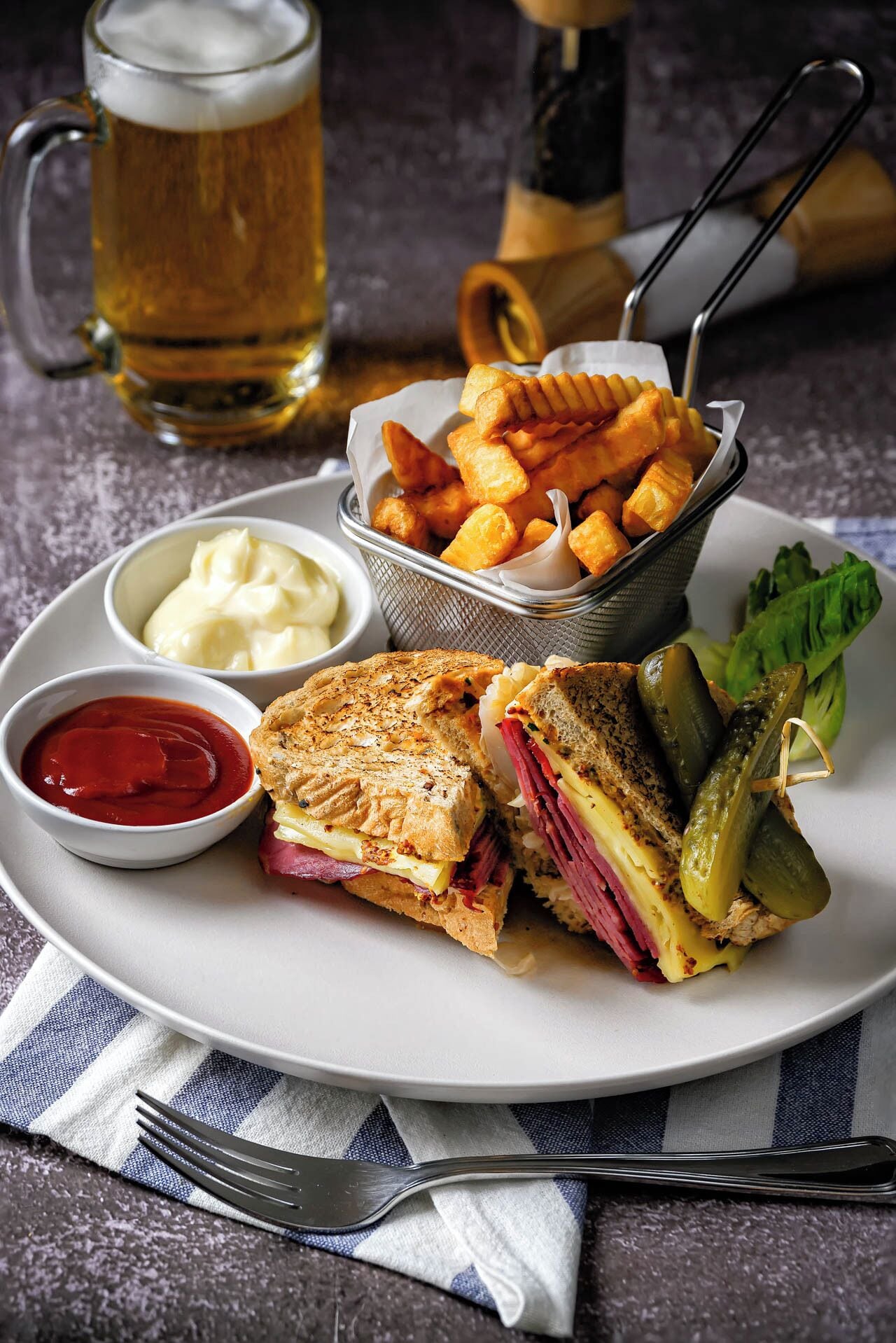 A plate with a sandwich, pickles, and a side of fries.