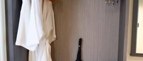 A walk-in closet with hanging robes, a guitar, a radio, and a pair of shoes.