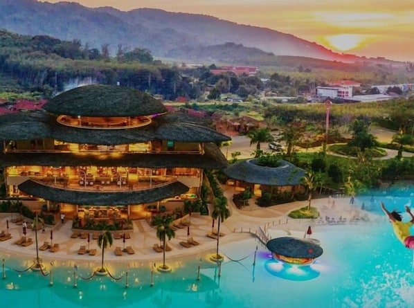 A resort with a large pool, multiple dining areas, and a view of the surrounding landscape. - Amora Beach Resort Phuket (Choeng Thale)