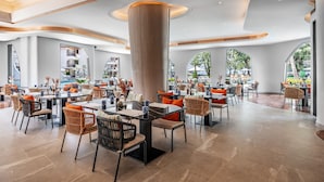 Un amplio comedor interior con mobiliario moderno y ventanas grandes que ofrecen vistas al exterior.
