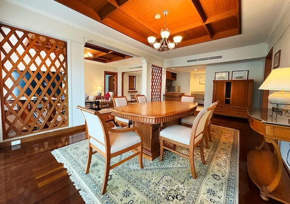 Un comedor con una mesa redonda de madera rodeada de sillas, un tapete estampado y muebles de madera.