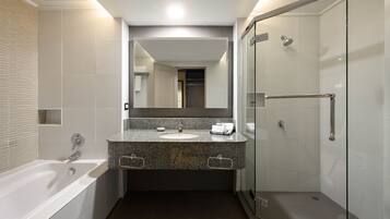 Un baño moderno con una bañera, un lavabo con encimera de granito y una ducha con mampara de vidrio.