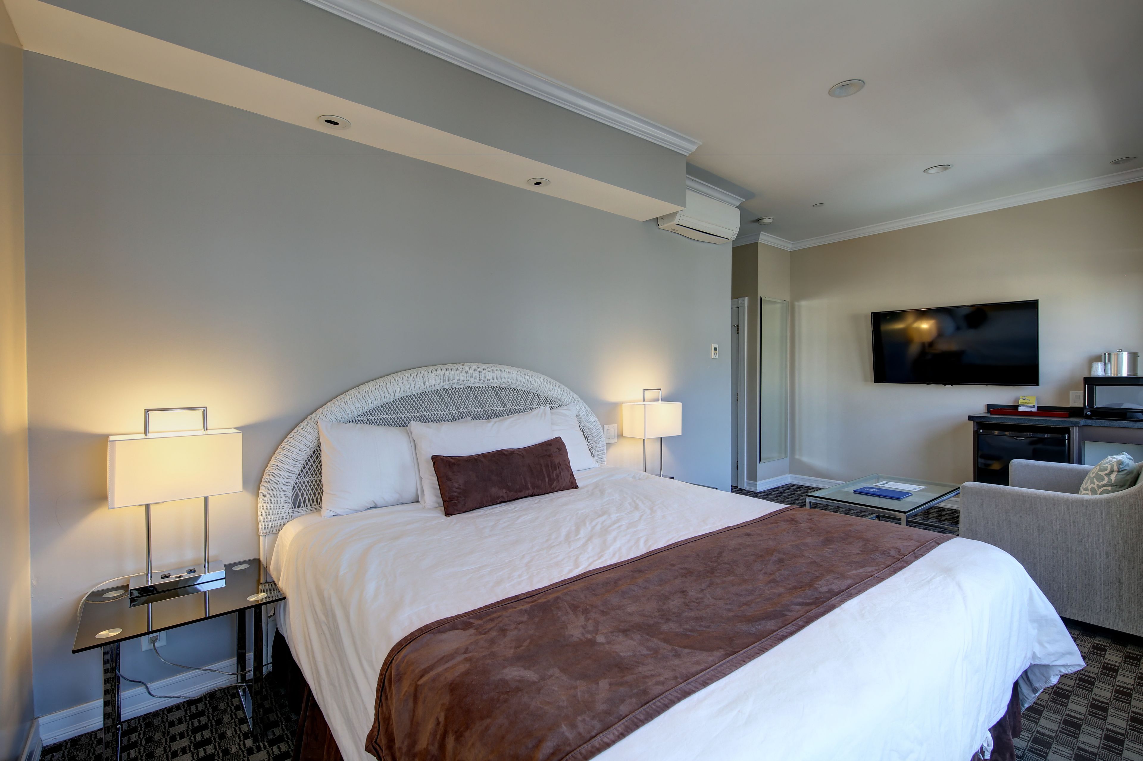 Habitación de hotel con una cama grande, dos lámparas de noche, un televisor de pantalla plana, un escritorio con una silla y una mesita.