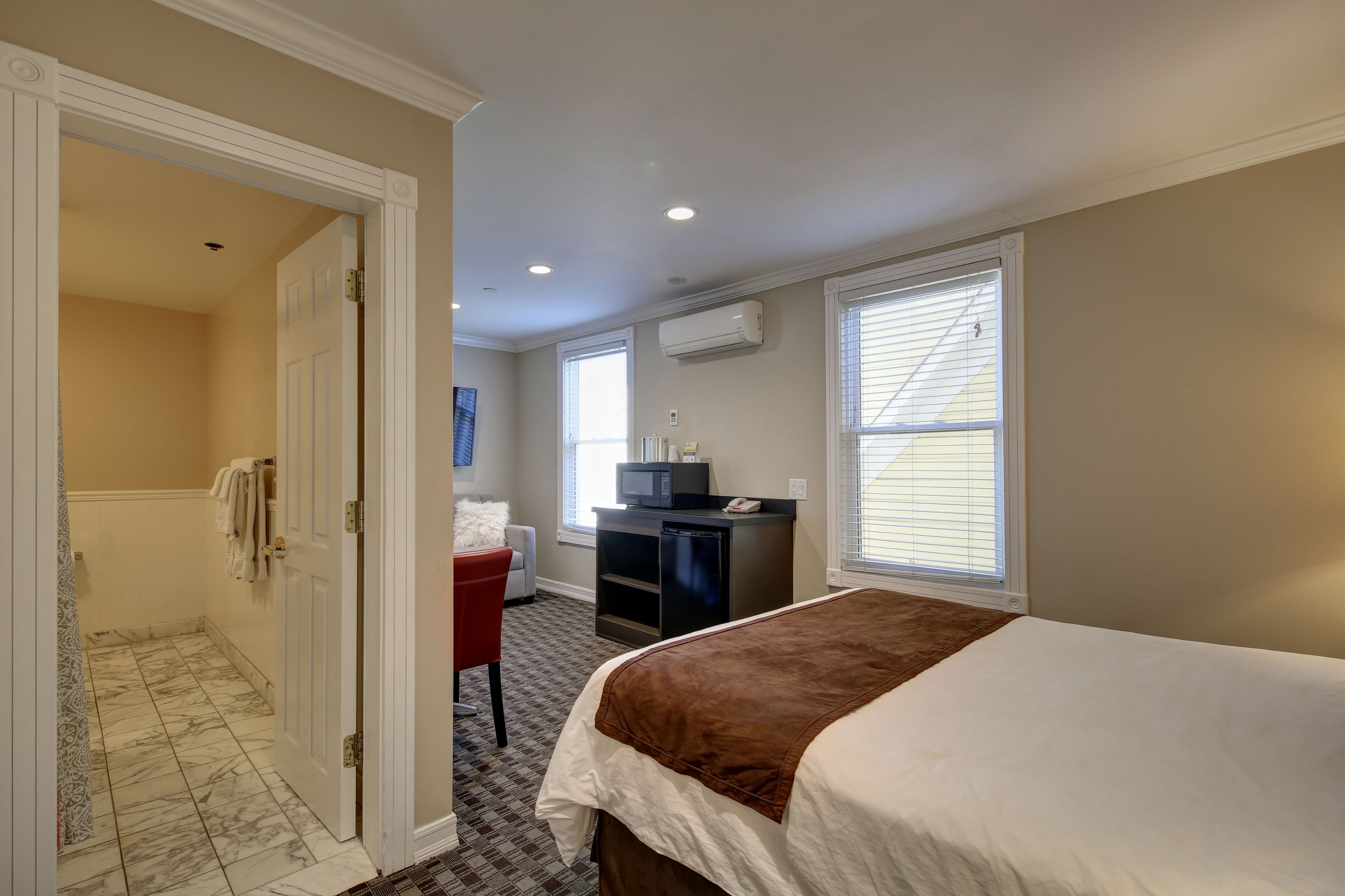 Une chambre d’hôtel équipée d’un lit, d’un bureau avec un ordinateur, d’un climatiseur et d’un espace douche.