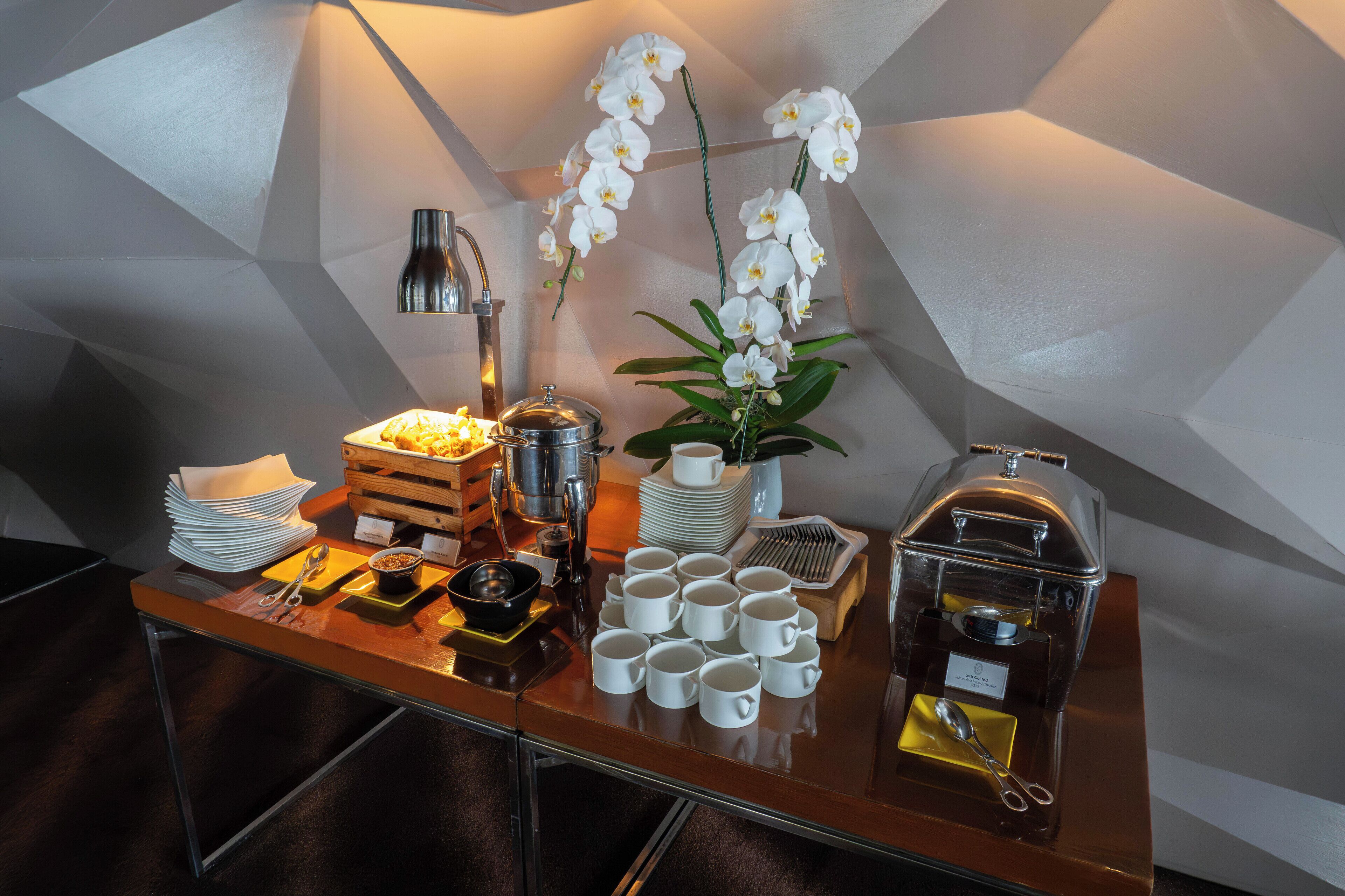 A breakfast buffet setup with various food items, utensils, and a coffee machine.
