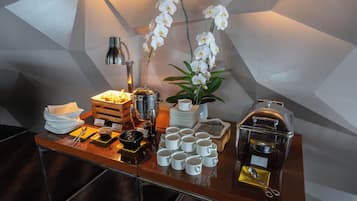 Montaje de un bufé de desayuno con diversos alimentos, utensilios y una máquina de café.